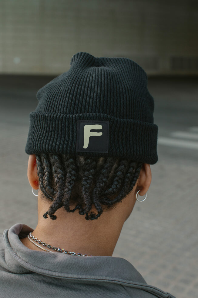 Dark beanie on person showing cream colored label patch with letter F logo