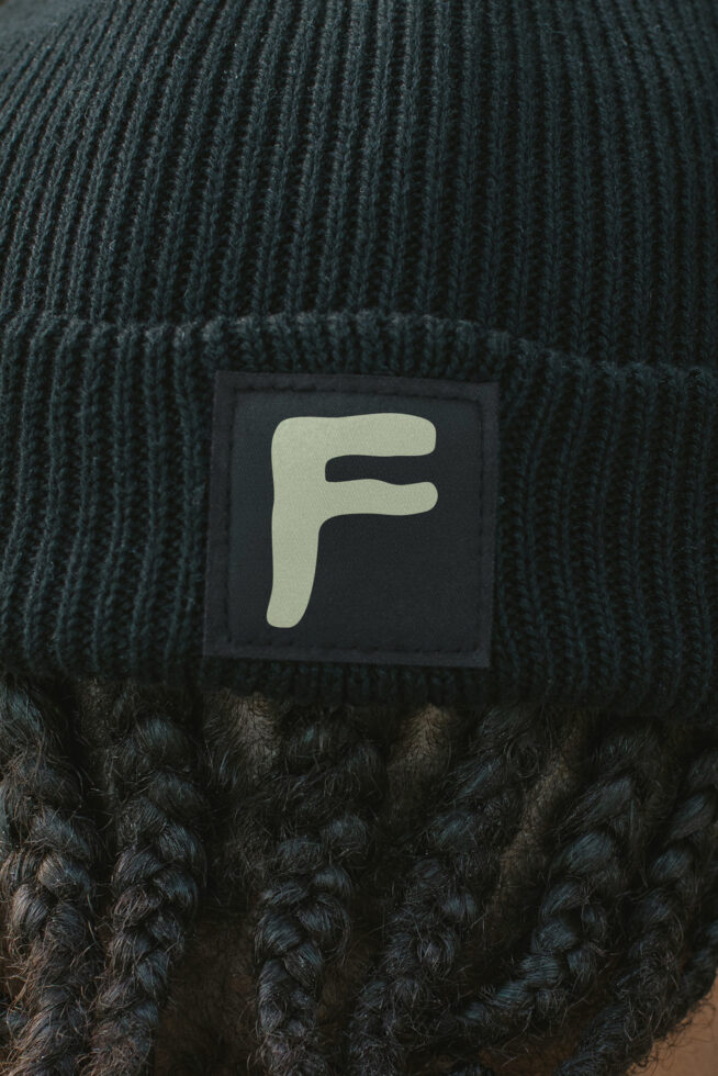 Beanie label mockup close up on dark knit fabric texture