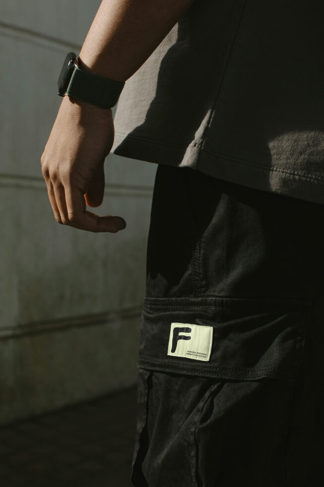 Cream label on black cargo pants pocket with person wearing smart watch