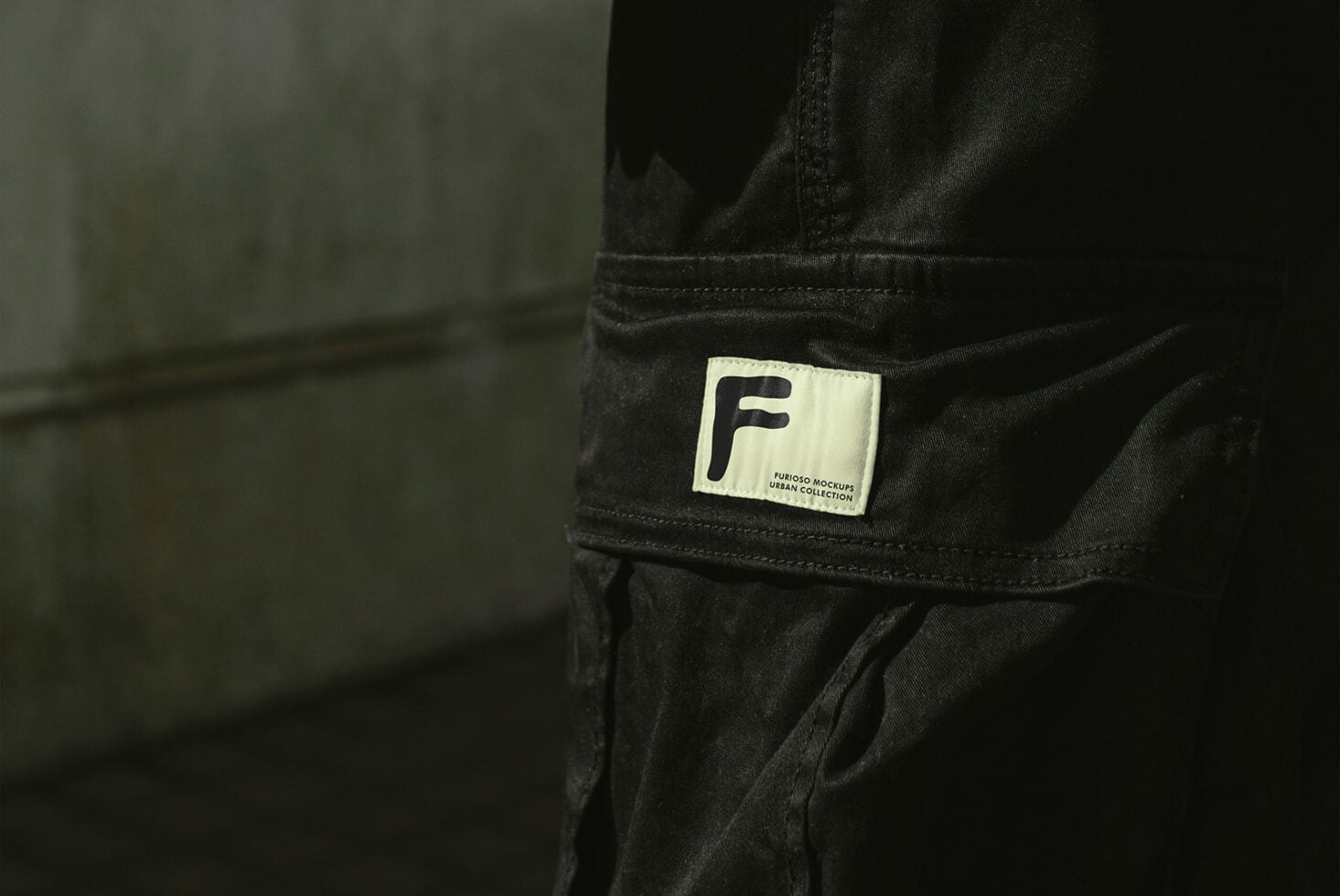 Cream label with F logo on black cargo pants pocket close up