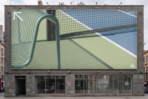Rooftop billboard displaying tennis court with net, shadows, blue sky