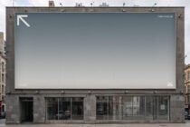 Rooftop billboard with gradient gray fade, minimal logo in corner