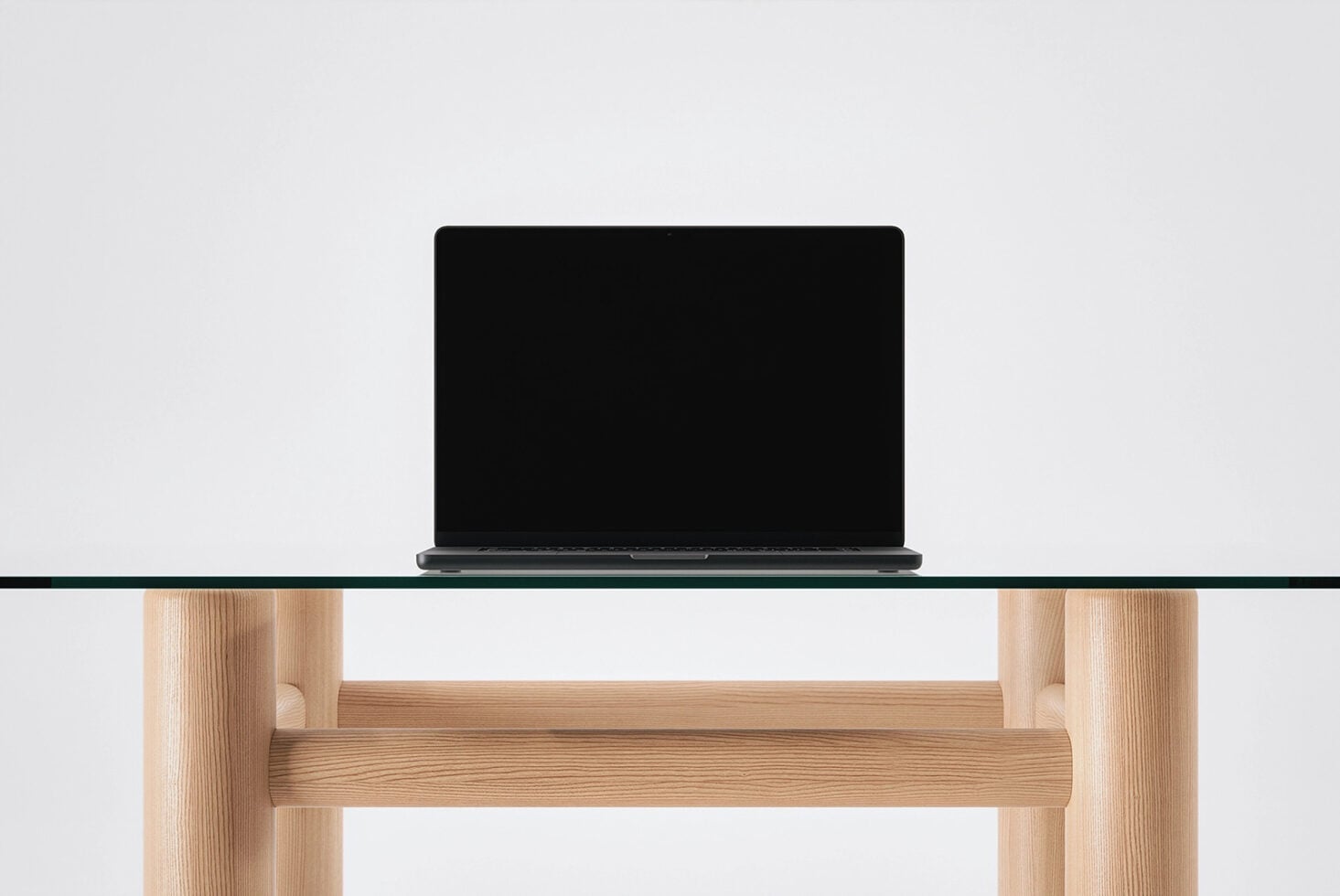 Dark laptop sitting on light glass shelf with natural wood frame below