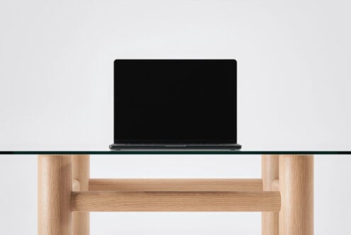 Dark laptop sitting on light glass shelf with natural wood frame below