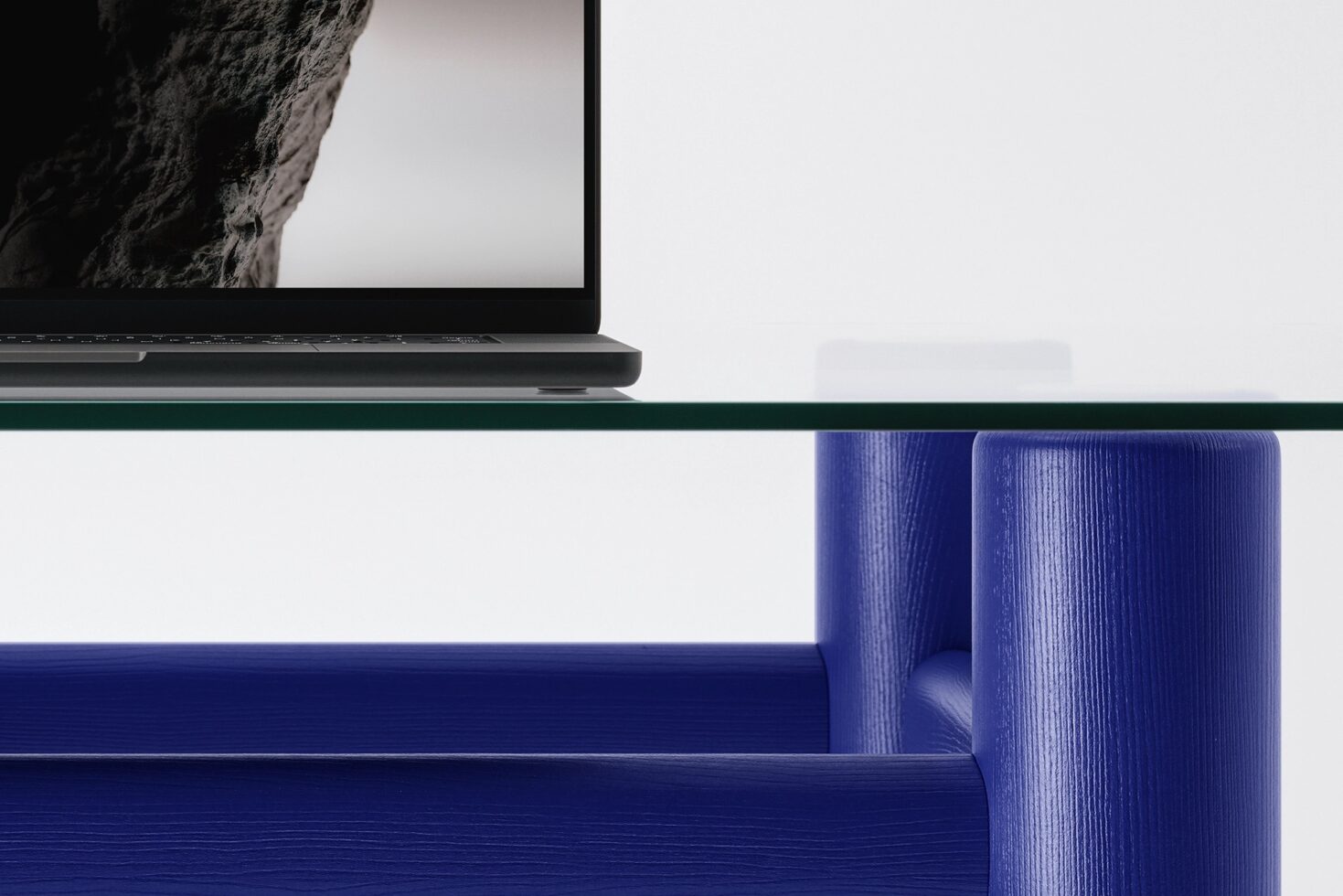 Laptop on glass shelf above blue textured modern furniture piece