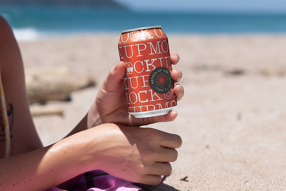 Slim can mockup with rust orange design held on beach with sunburned arm visible