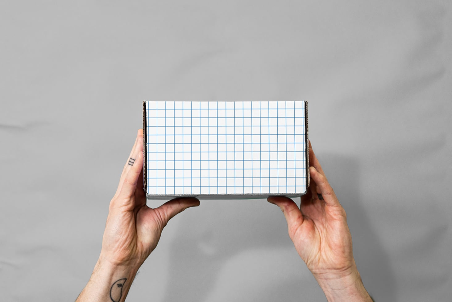 Hands holding open notebook with blue grid pattern on gray background