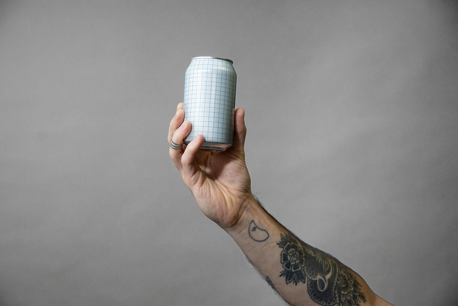 Hand holding single aluminum can with blue grid pattern mockup