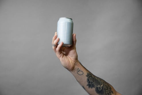 Hand holding single aluminum can with blue grid pattern mockup