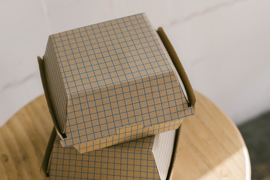 Stacked kraft boxes mockup with grid pattern on round wood chair