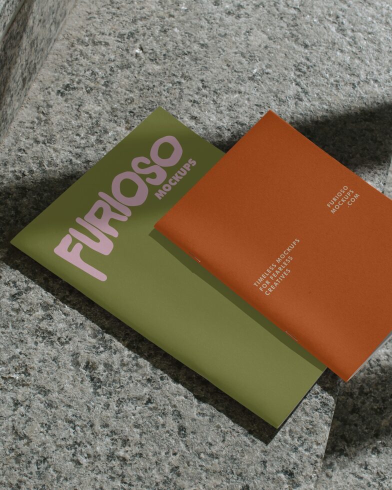 Olive green card with pink text next to rust colored card on concrete