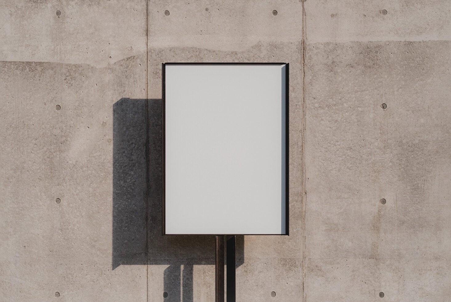 Black framed poster on concrete wall showing empty white space with shadow
