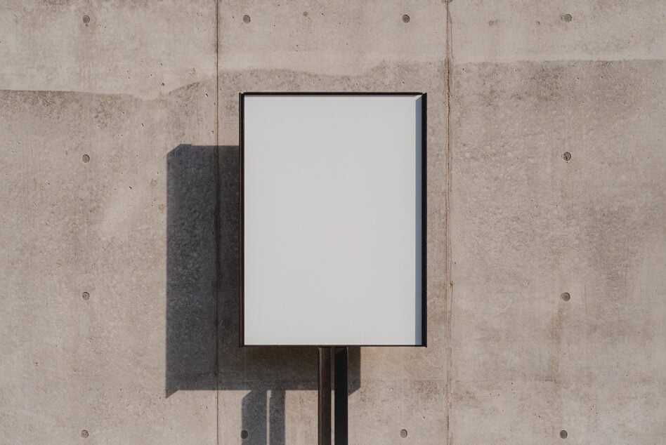 Black framed poster on concrete wall showing empty white space with shadow