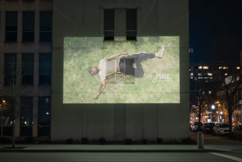 Overhead shot of person lying on grass displayed on urban billboard