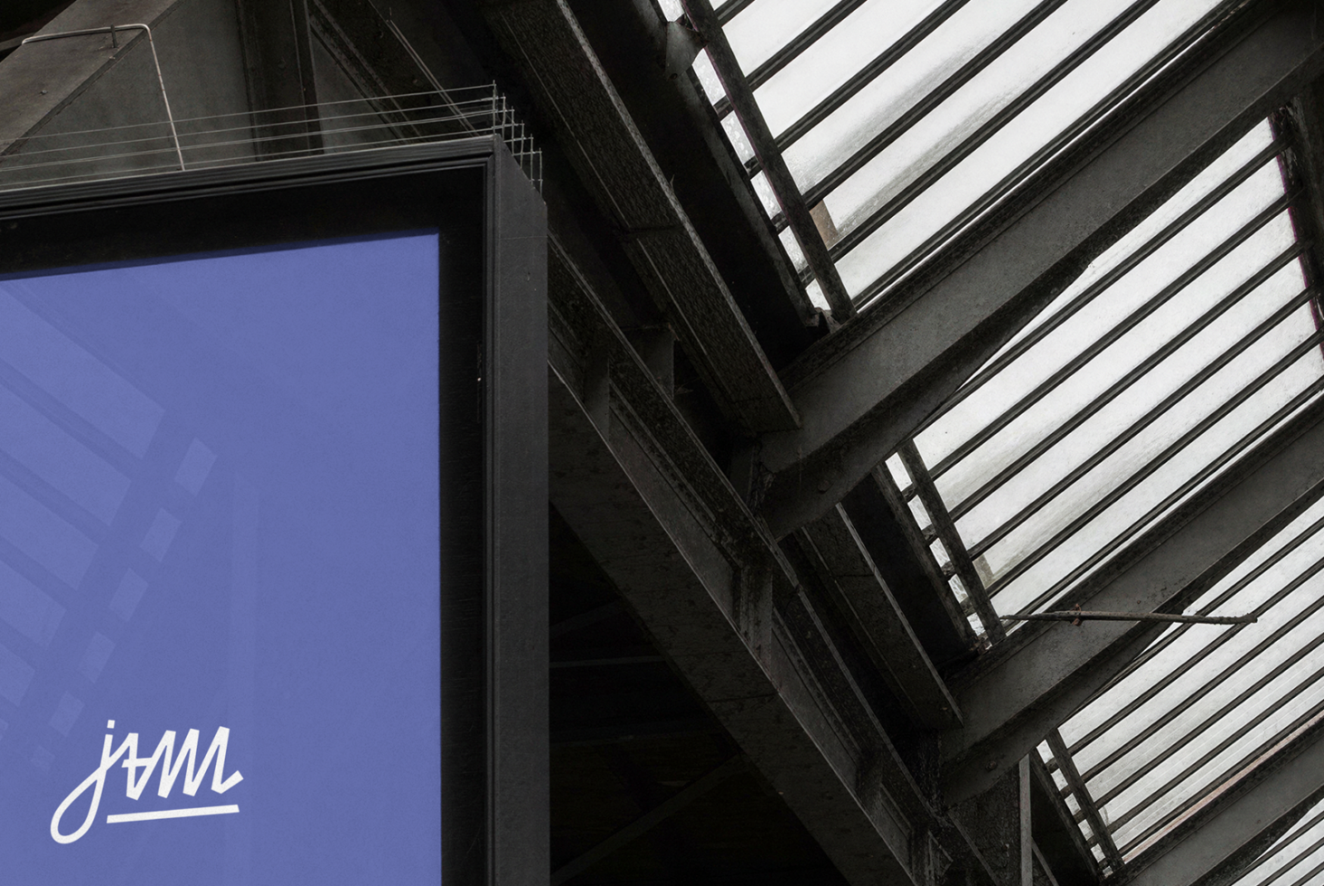 Blue screen with jvmi logo under industrial ceiling with skylight panels