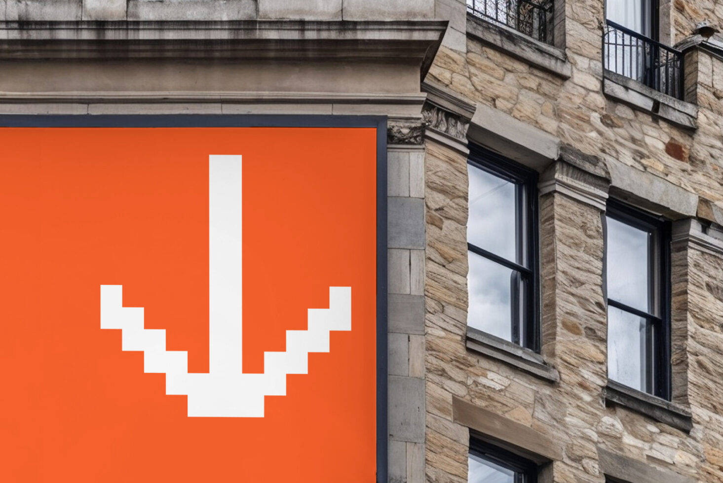 Orange billboard with white pixelated smiley face next to stone building