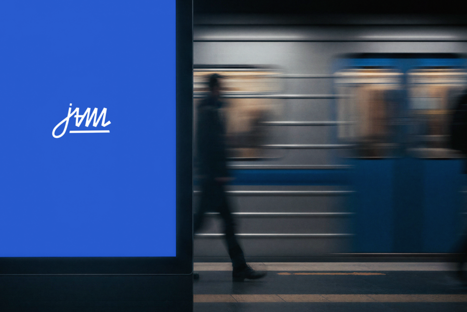 Blue wall with cursive jvmi logo beside blurred subway train passing by