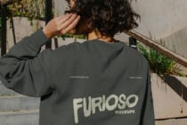 Back view of dark crewneck with pink graphic on outdoor steps
