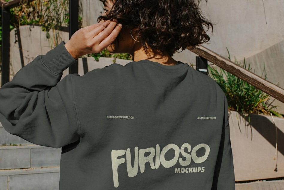 Back view of dark crewneck with pink graphic on outdoor steps