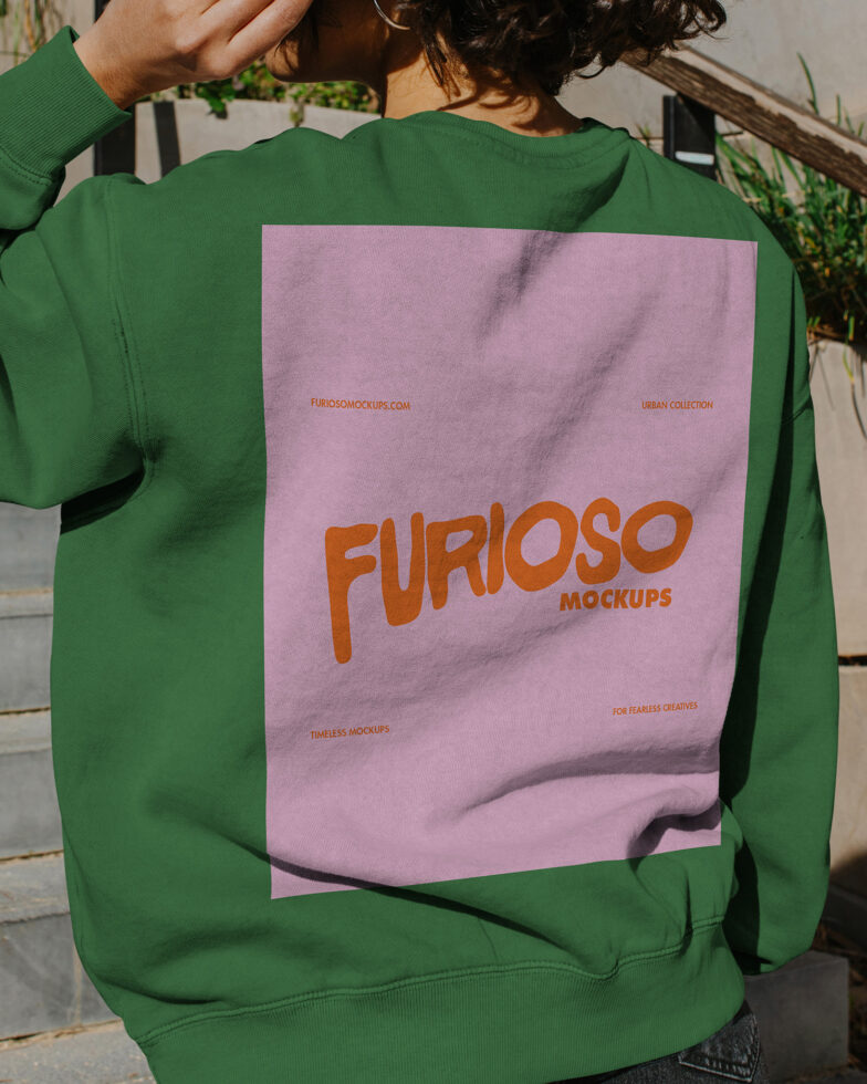 Person wearing green crewneck with pink graphic panel on back