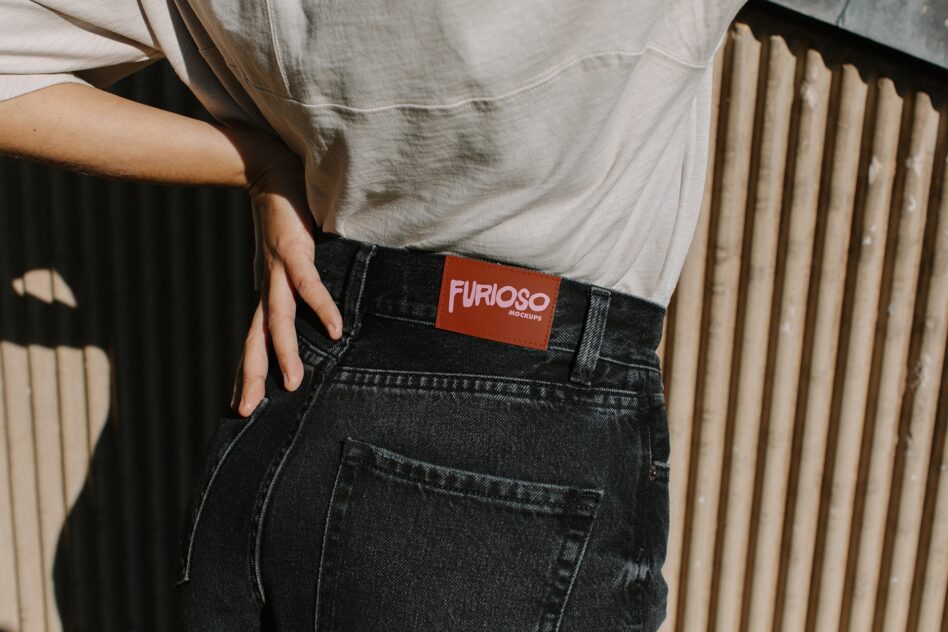 Rust orange fabric tag with pink Furioso text on jeans at hip level