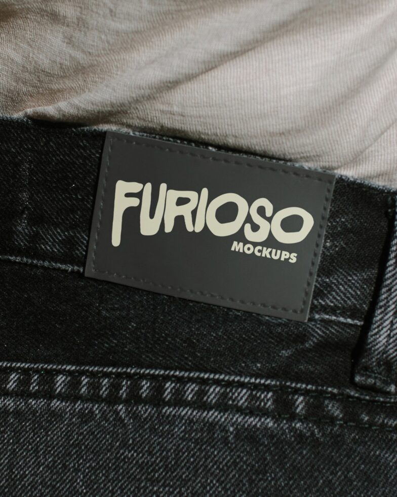 Black woven label with white Furioso text stitched onto dark denim fabric