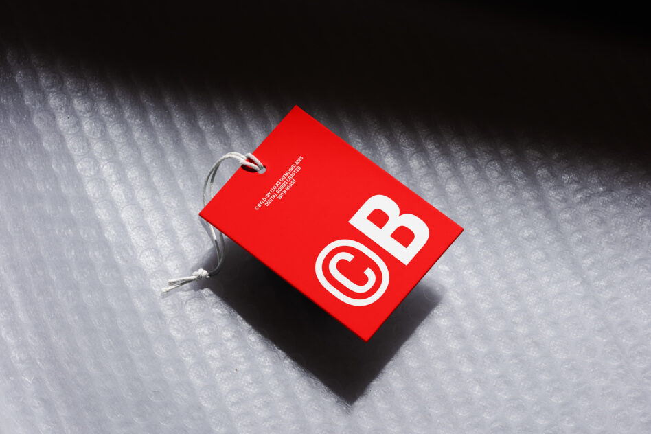 Red gift tag with CB logo on concrete textured surface with string