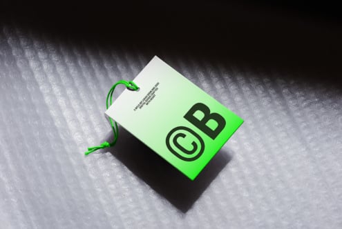 Bright green hang tag mockup with black logo on textured concrete surface