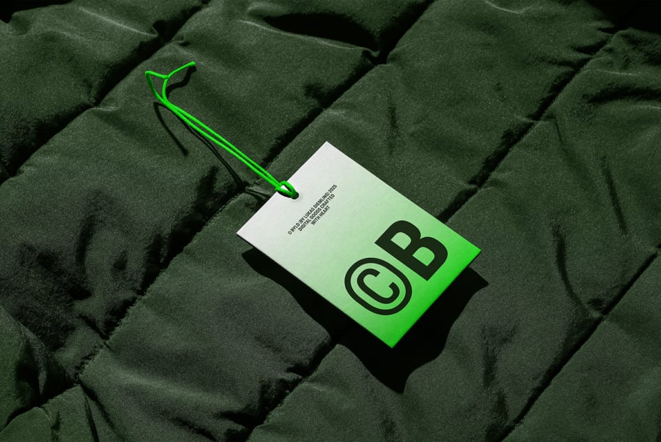 Green business card with CB logo on quilted fabric background with stylus