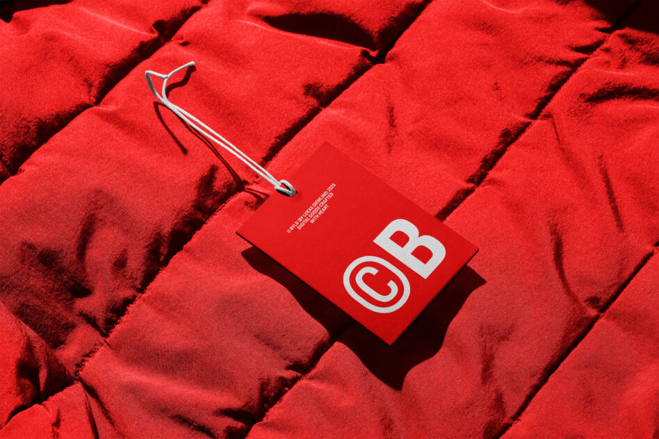 Red business card with CB logo on quilted fabric background with stylus