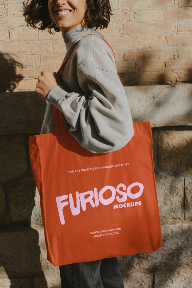 Woman wearing cream jacket holding bright orange tote bag outdoors