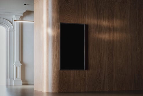 Empty black frame hanging on wooden wall next to white interior doorway