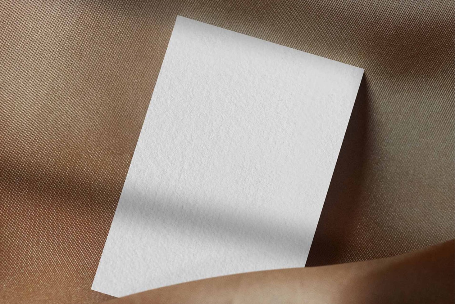 Blank white folded card on neutral beige fabric backdrop