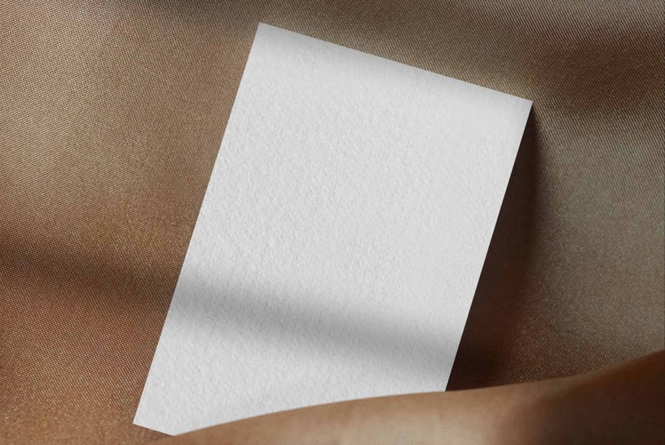 Blank white folded card on neutral beige fabric backdrop