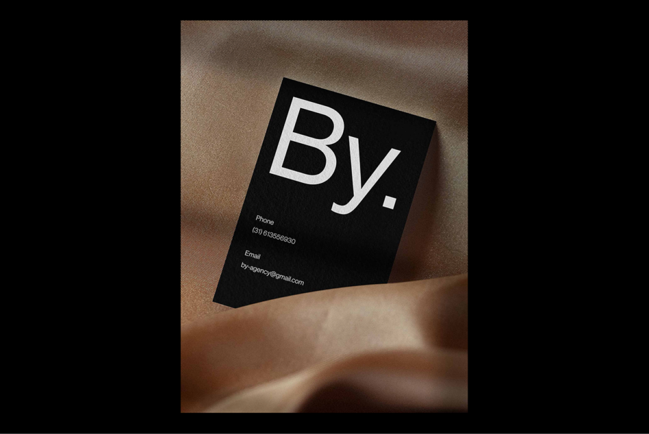 Black business card mockup on elegant fabric texture featuring bold white typography and contact details suitable for designers marketing branding templates.