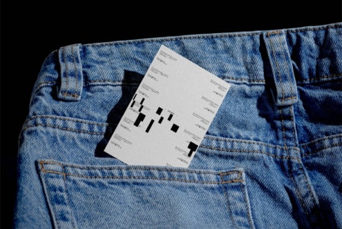 Cream business card tucked in back pocket of light blue denim jeans