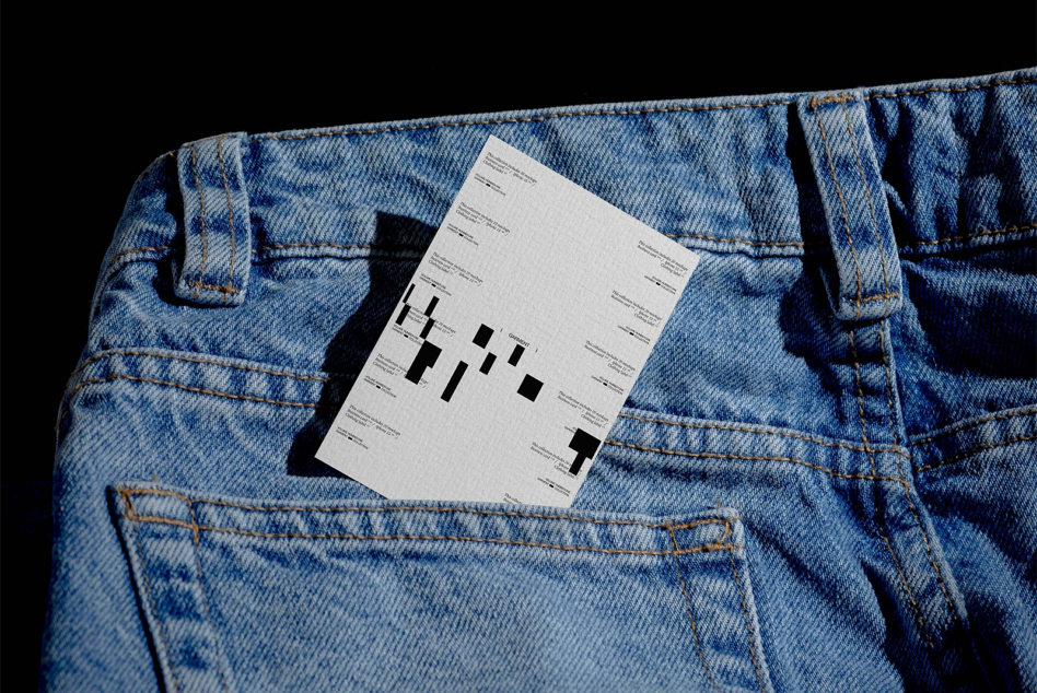 Cream business card tucked in back pocket of light blue denim jeans