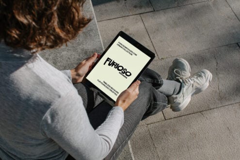 Overhead shot of person sitting on concrete holding tablet with cream screen displaying Furioso branding