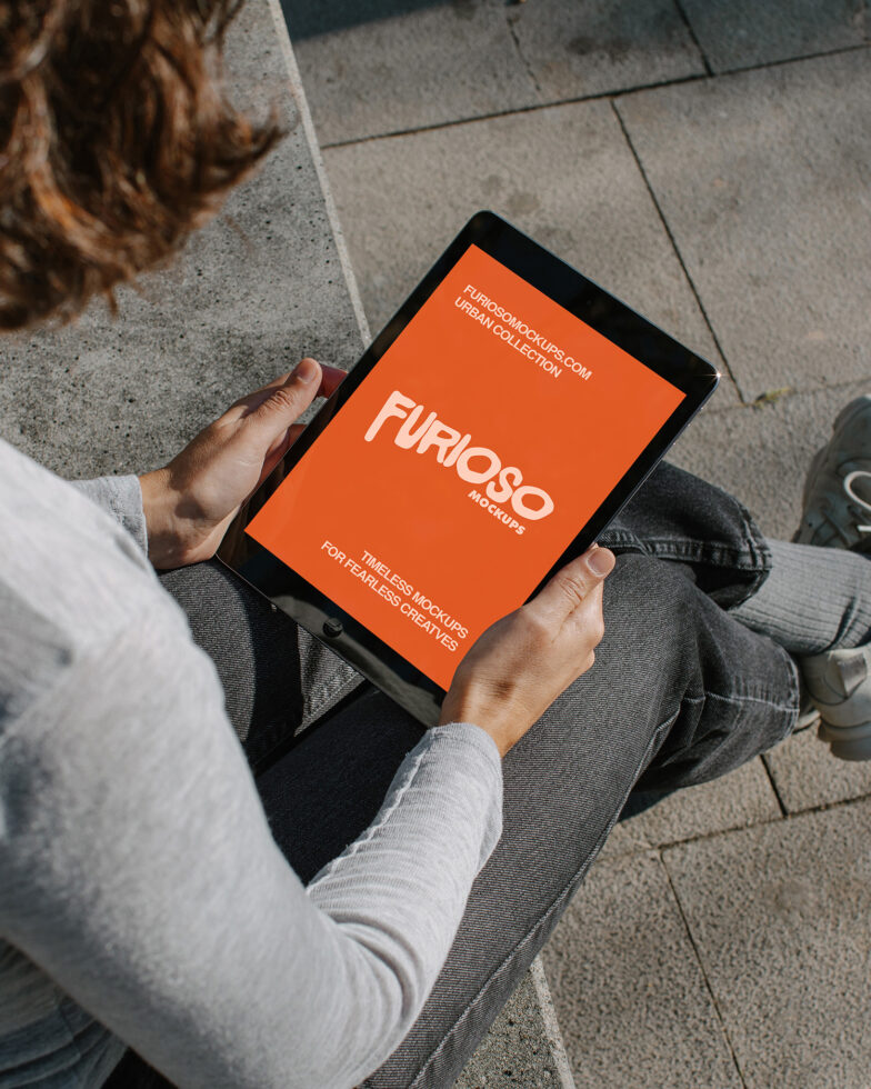 Overhead shot person holding bright orange tablet mockup on stone ground