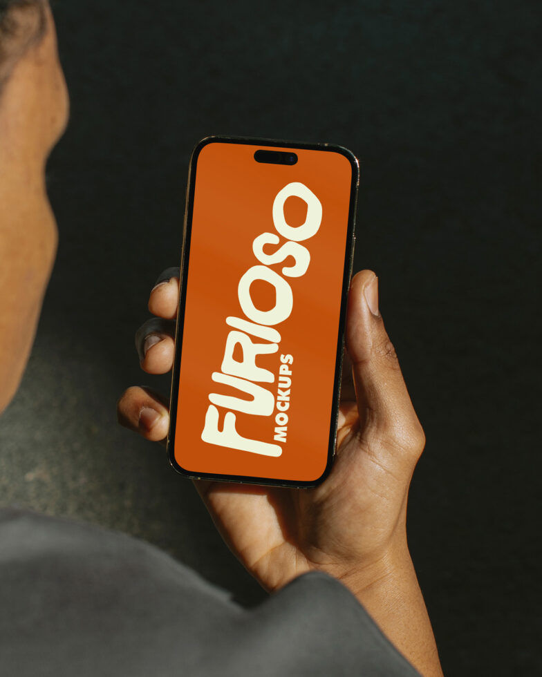 Hand holding phone with orange screen displaying white Furioso Mockups text against dark background