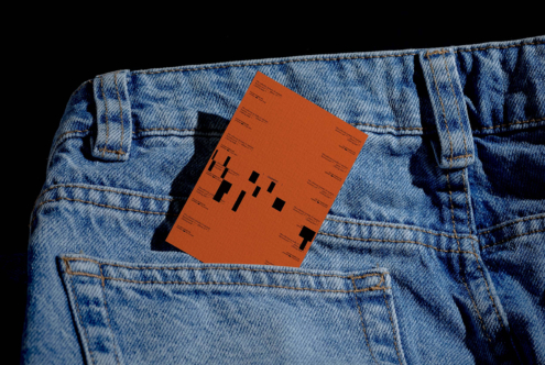 Orange business card tucked in back pocket of light blue denim jeans