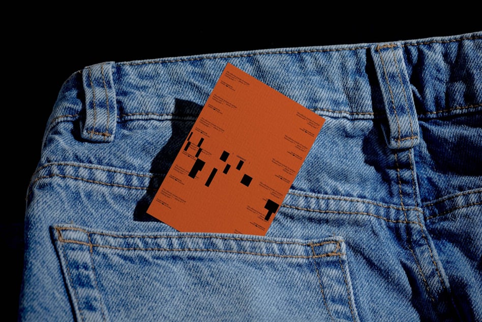 Orange business card tucked in back pocket of light blue denim jeans