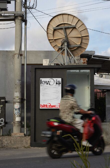 Poster mockup on urban street kiosk with satellite dish above, blurred scooter passing by