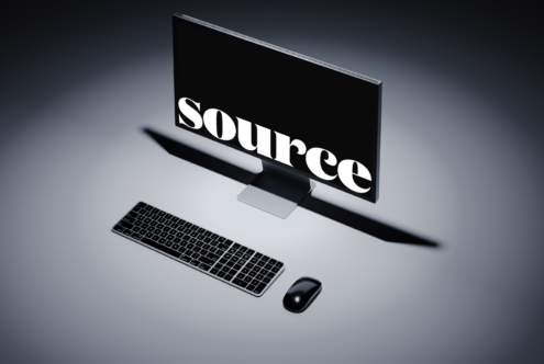 Desktop monitor displaying SOURCE in thick serif typeface with keyboard