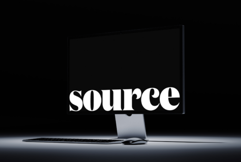 Monitor displaying SOURCE in bold serif font with wireless peripherals