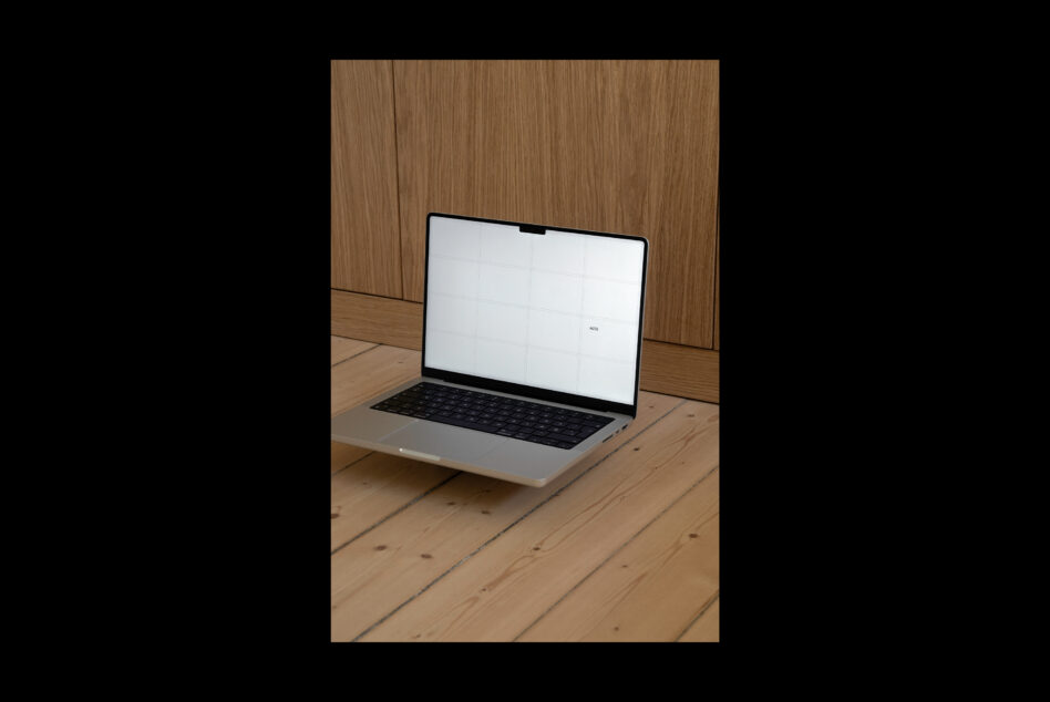 Laptop on wooden desk against oak paneled wall with minimal lighting