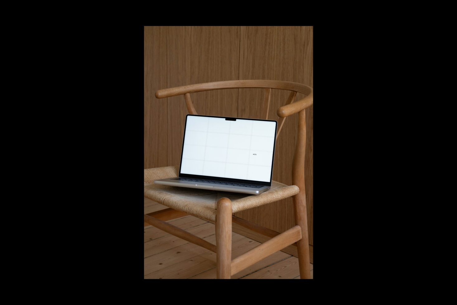 Laptop on wooden chair displaying blank grid template, mid-century modern aesthetic