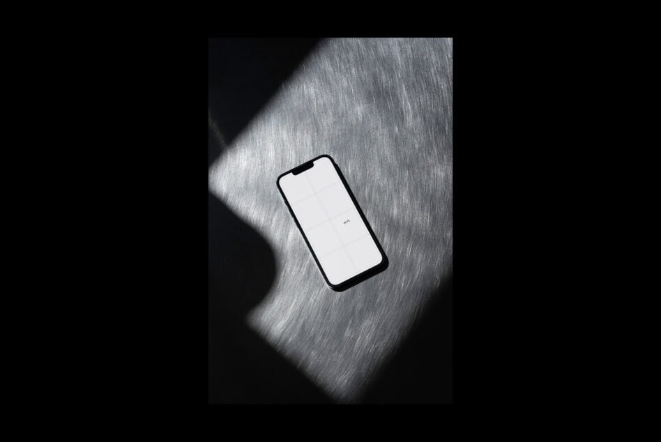 Phone with white screen under dramatic light beam on textured gray surface