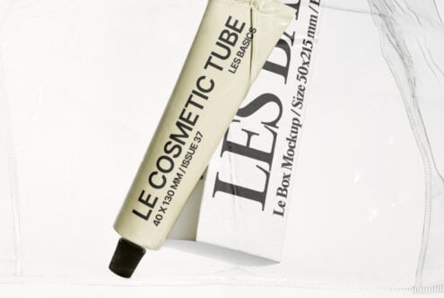 Beige cosmetic tube beside white box mockup on soft fabric background
