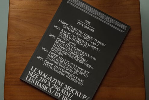 Black magazine mockup angled on wood table showing fabric content details
